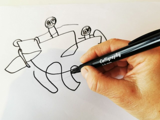 Her tegner en voksen over med en sort tusj, og visker bort blyantstrekene.